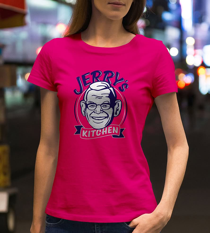 Woman wearing a bright pink t-shirt with a cartoon-style logo of a smiling older man and the text "Jerry's Kitchen" in a busy nighttime city scene.