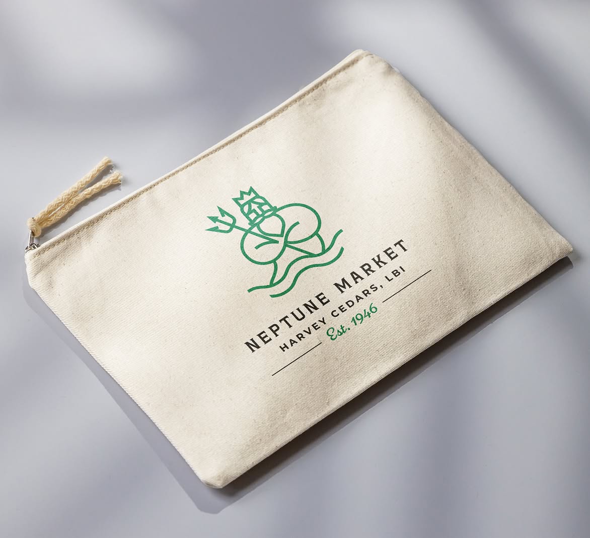 NeptuneMarket-Pouch A beige canvas pouch with Neptune Market logo consisting of a green Neptune illustration and black text reading "Neptune Market, Harvey Cedars, LBI, Est. 1946."