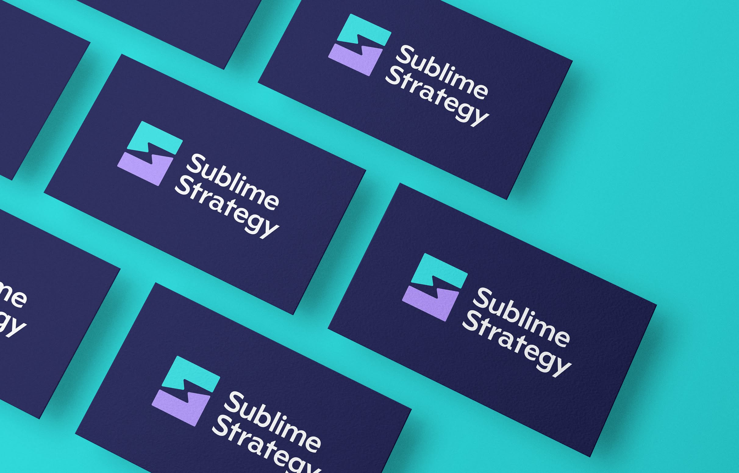 Sublime-BusinessCards Multiple blue business cards, each with the Sublime Strategy logo, sit on a teal background. The logo is made up of a teal and purple icon forming a lightning bolt in the negative space with the text "Sublime Strategy" in white.