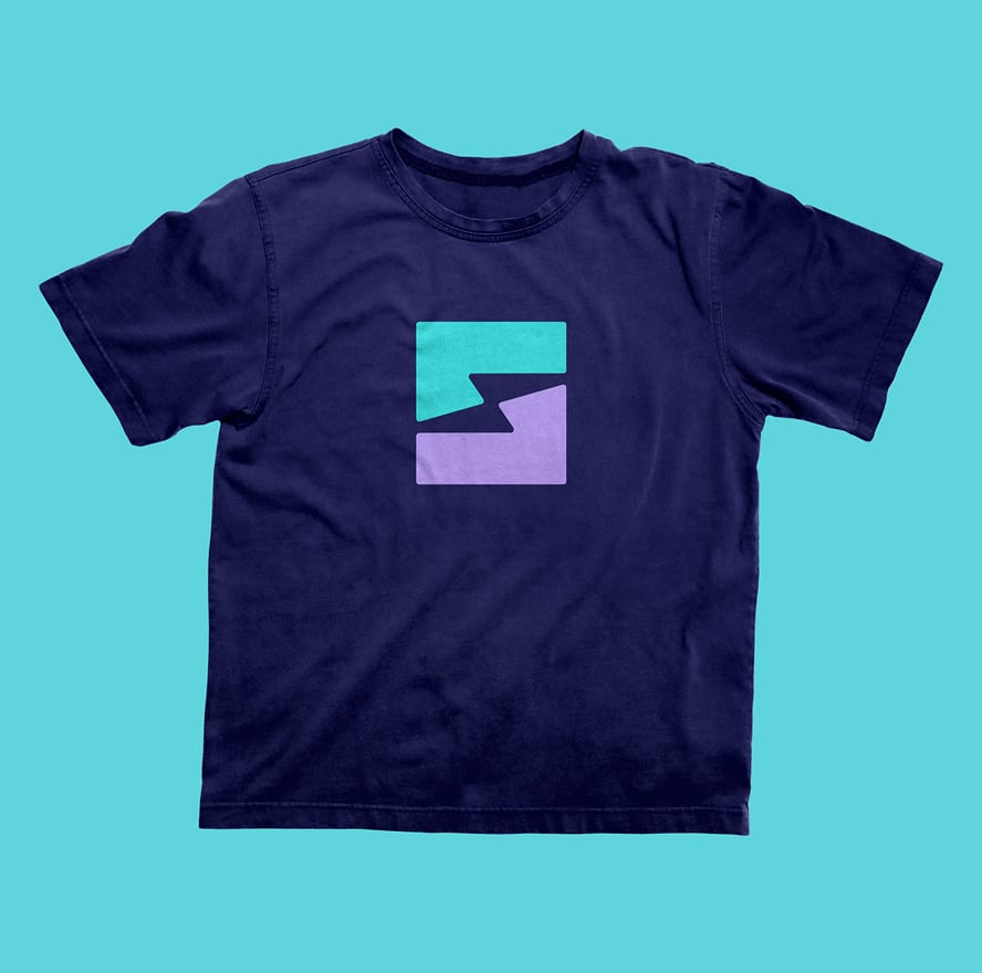 Sublime-Shirt Navy blue T-shirt with abstract logo. Logo has teal and purple shapes forming a lightning bolt design in the center. Light blue background.