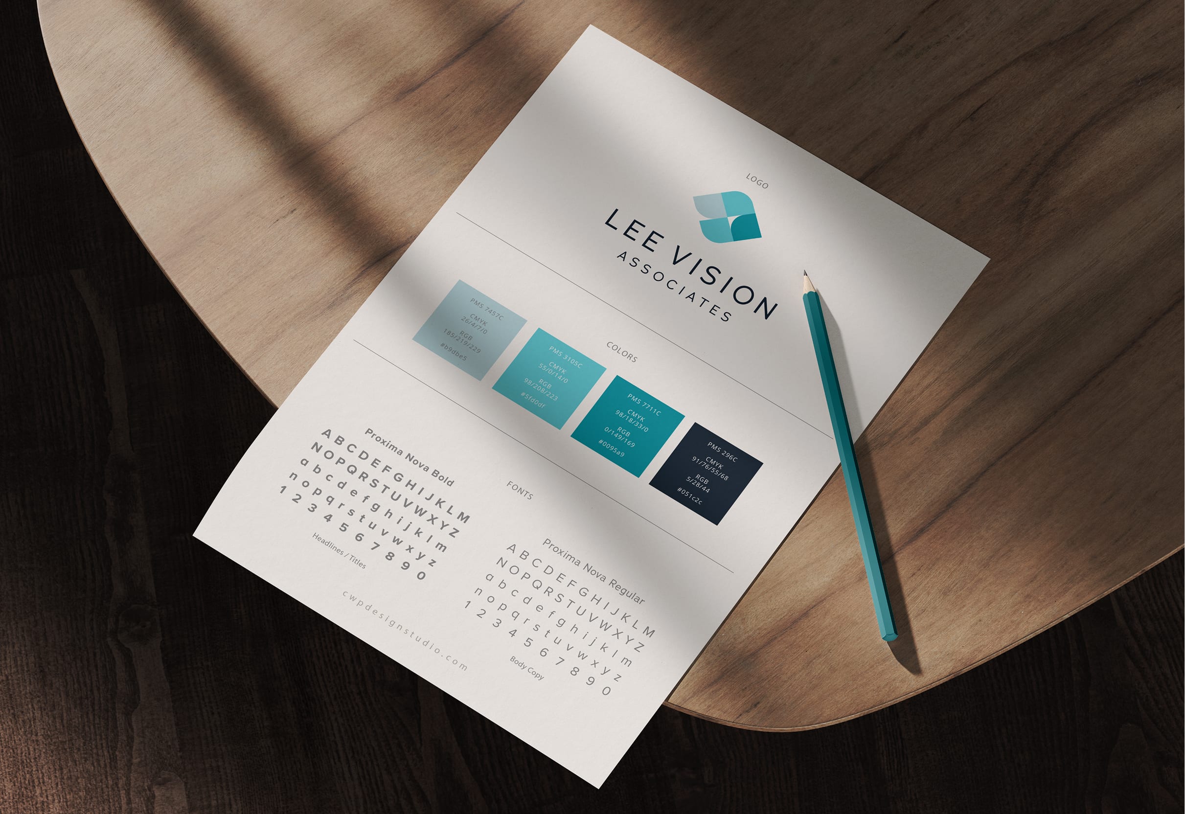LeeVision-Hero A style guide on a wooden table shows the logo "Lee Vision Associates," color palette with blue hues, and font styles. A pencil lies beside it.