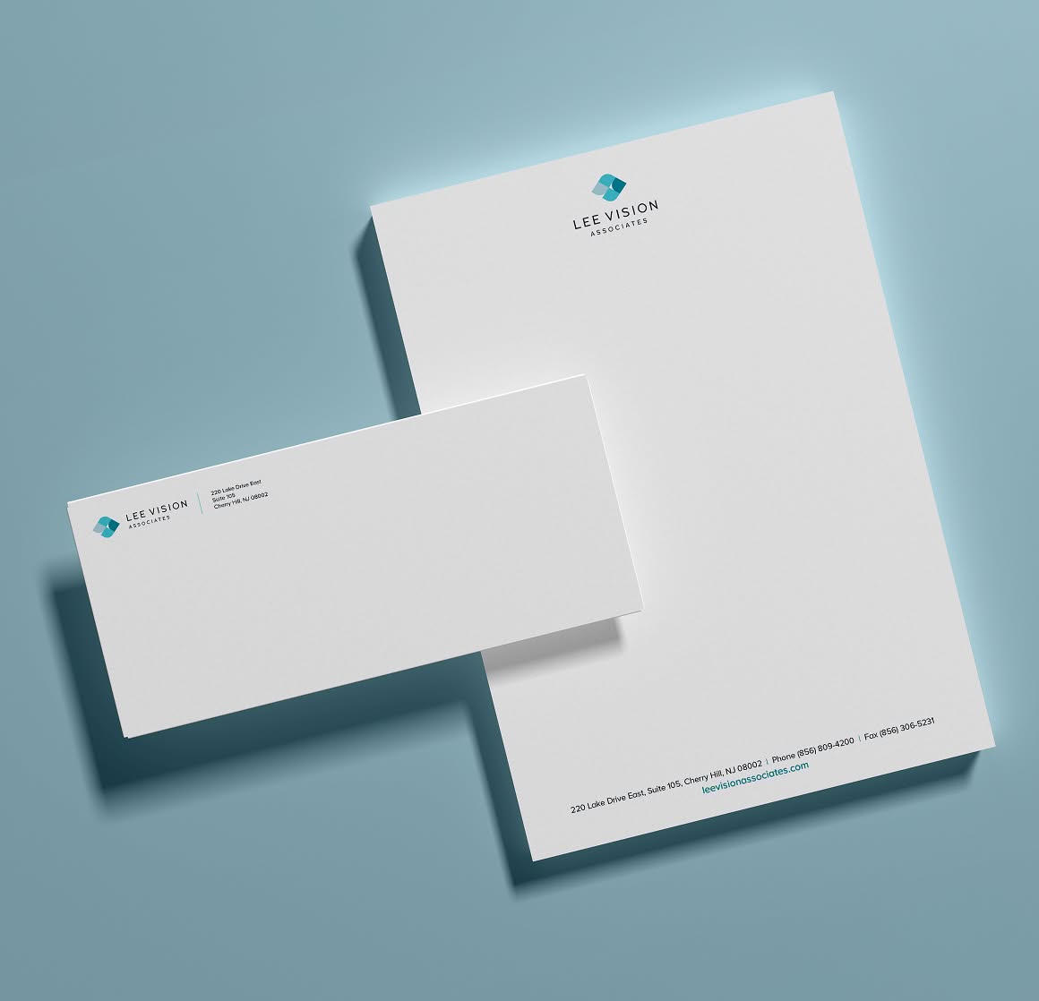 LeeVision-Stationery A modern stationery set for Lee Vision Associates with a white letterhead and envelope on a light blue background. Both feature a simple blue logo and text, conveying professionalism.
