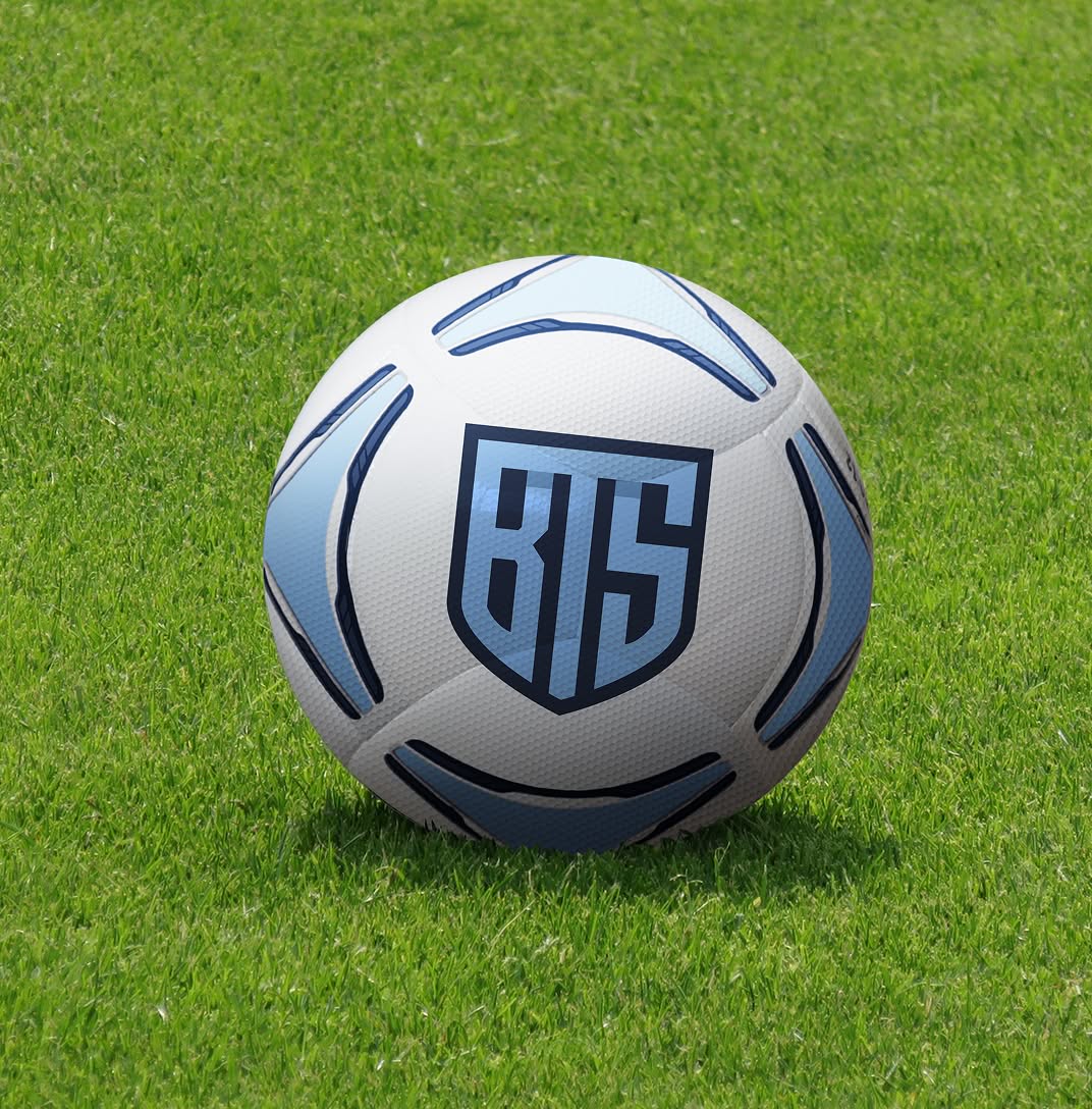 BTS-Ball A soccer ball includes a navy blue shield logo with the letters "BTS" in bright blue. The ball sits on vibrant green grass, conveying a sense of outdoor activity and sportsmanship.